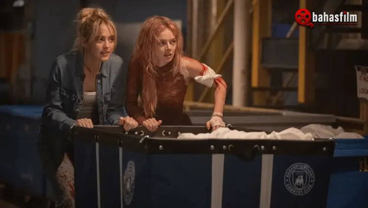 Samara Weaving berperan sebagai Grace, berdiri tegas dengan gaun rusak memegang senjata di rumah manor gelap pada sekuel film Ready or Not 2