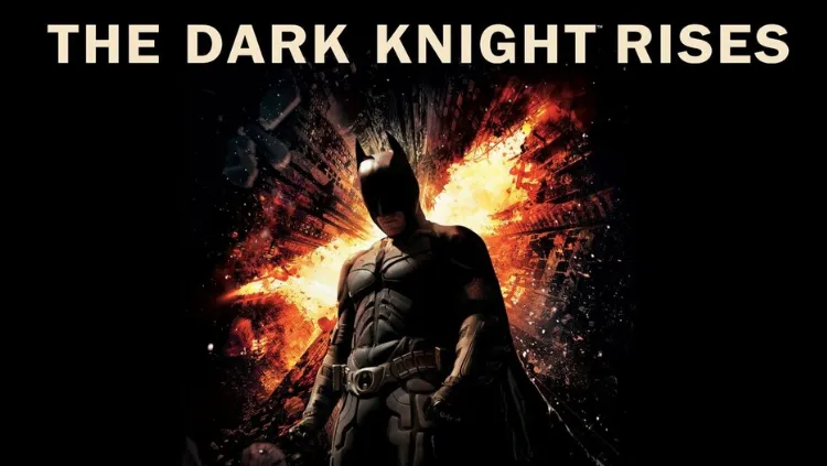Poster film The Dark Knight Rises menampilkan siluet Batman berdiri tegak di tengah reruntuhan gedung yang meledak membentuk lambang kelelawar dengan percikan api oranye dan latar belakang hitam pekat, terdapat teks besar "THE DARK KNIGHT RISES" di bagian atas.